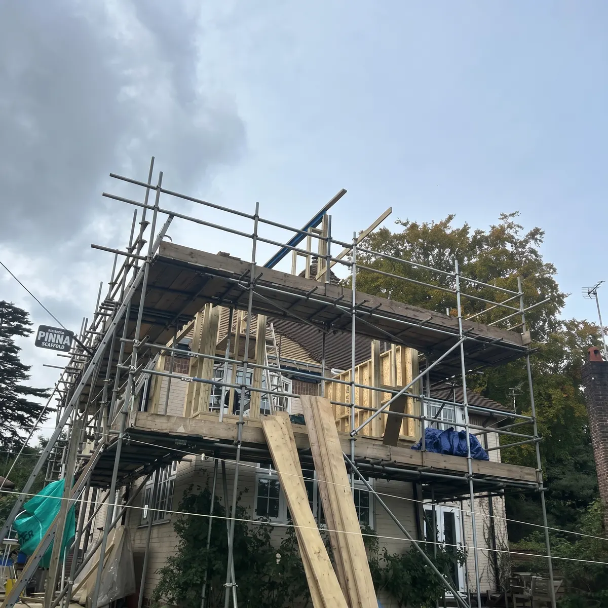 First floor extension under construction inside scaffolding, new roof timbers going on