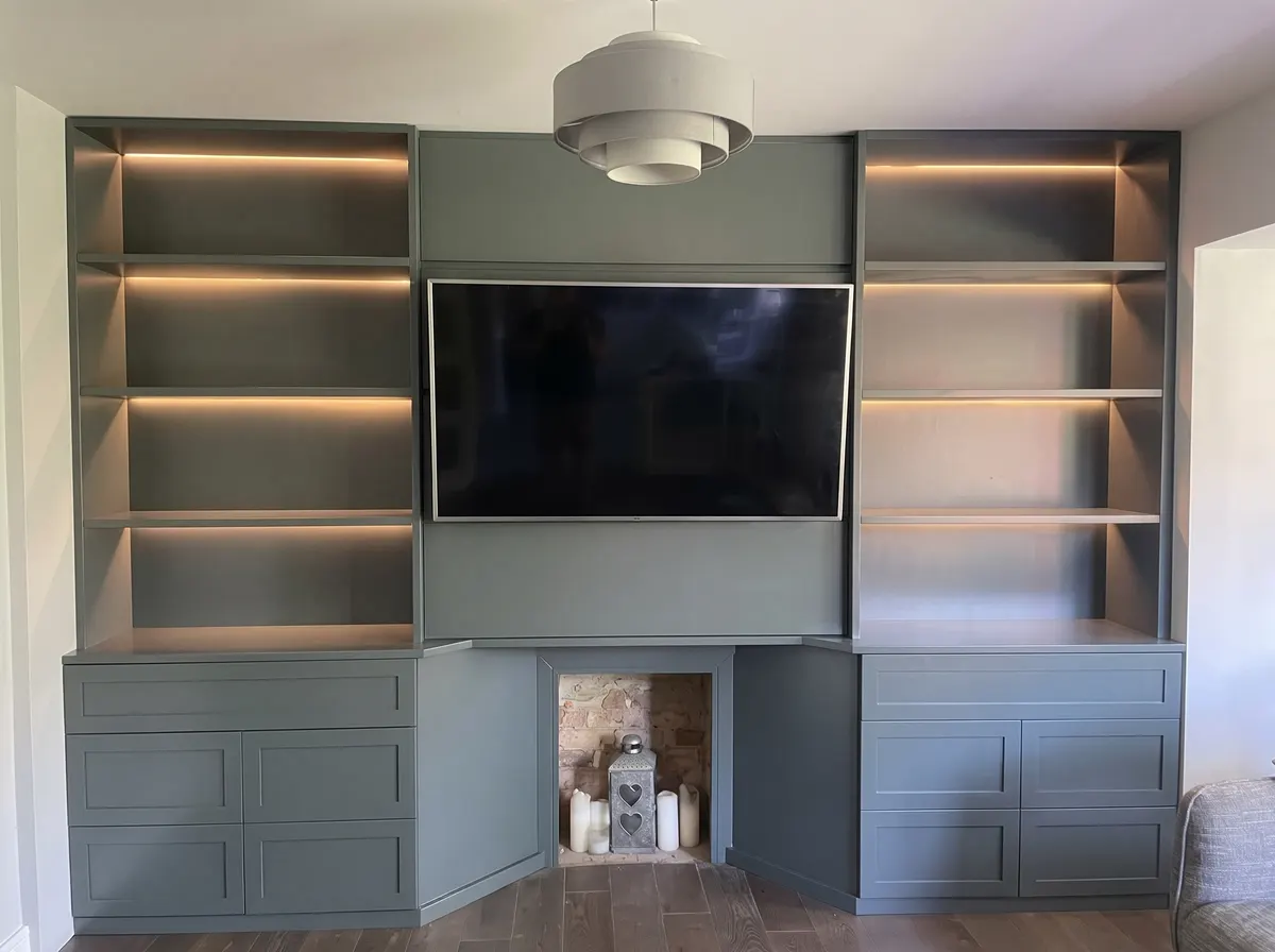 Bespoke painted media wall with lit open shelving either side of the television and cupboards below