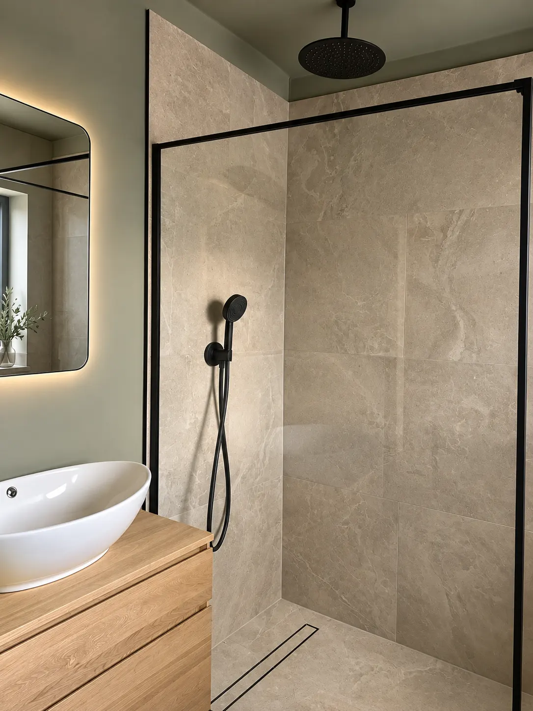 Walk-in shower with a matt black frame, rainfall head and large stone effect tiles